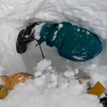 A snowboarder got buried upside down in snow. See skier's quick reaction.